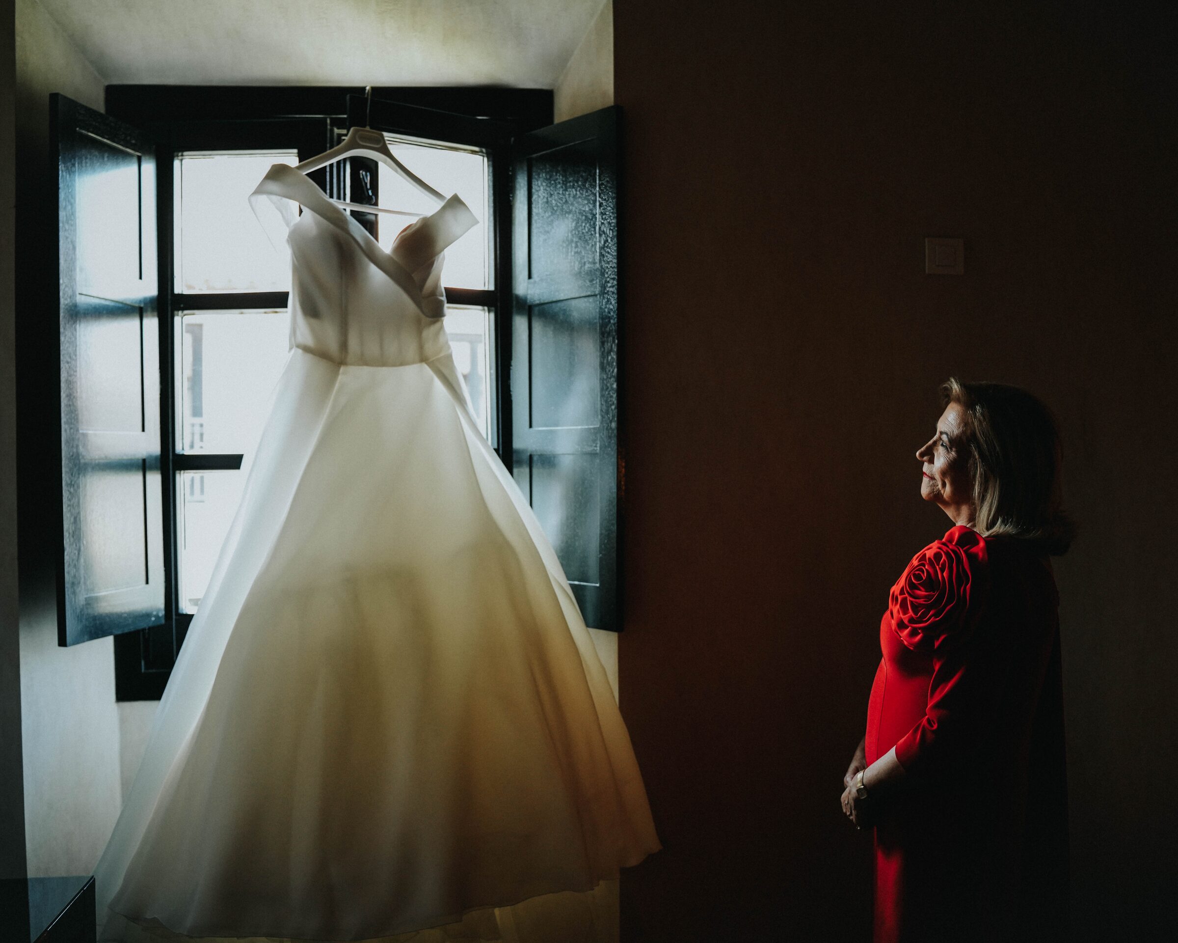 Madre en vestido rojo mirando el traje de novia